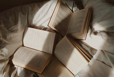 Different books placed on top of a bed.