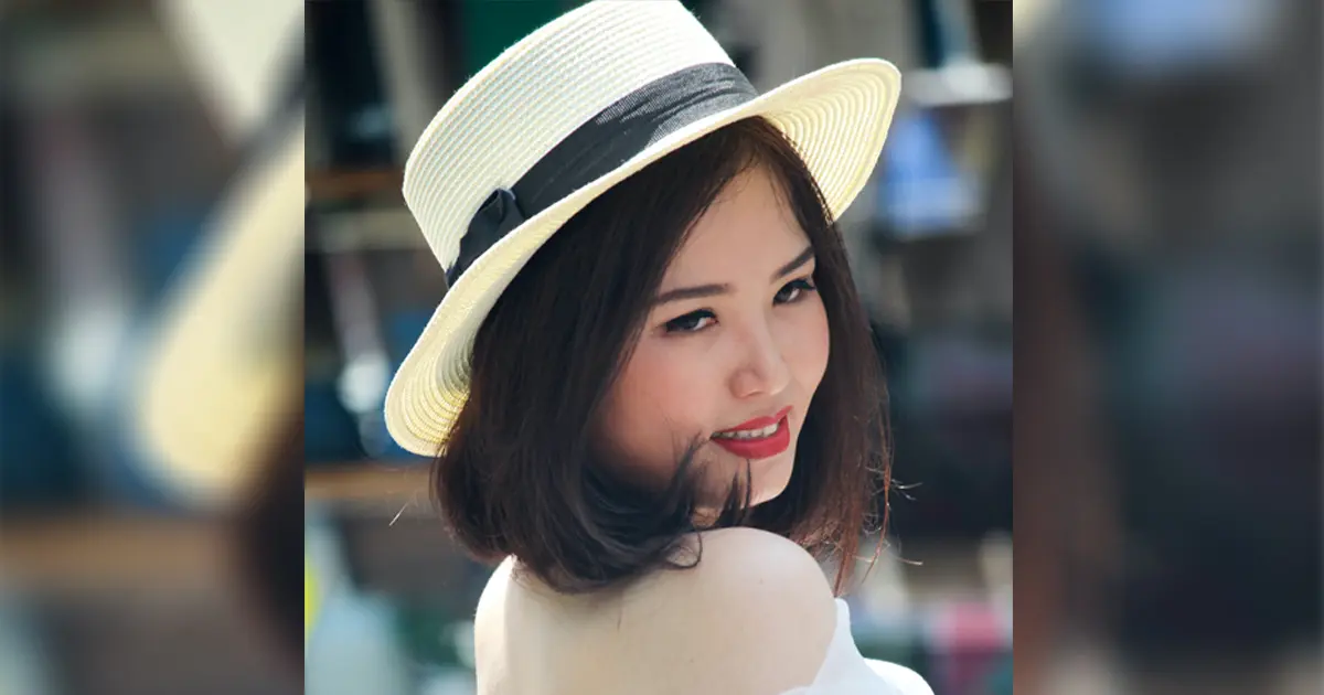 A photo of a beautiful Asian woman with short hair, wearing a white fedora and white off-shoulder top