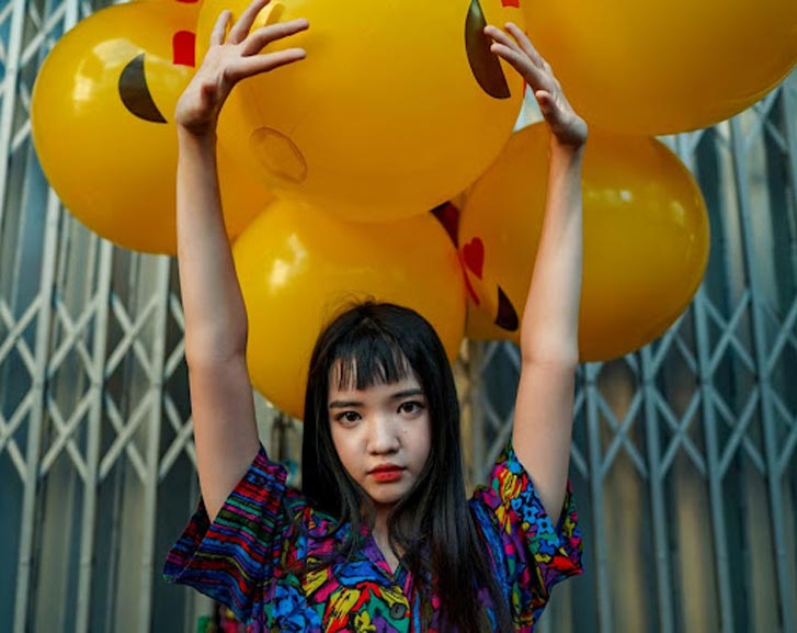 an Asian woman with yellow balloons